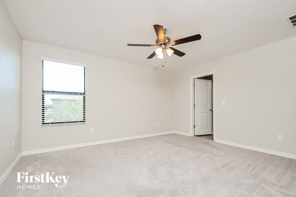 a spacious living room with a ceiling fan and a door to a closet