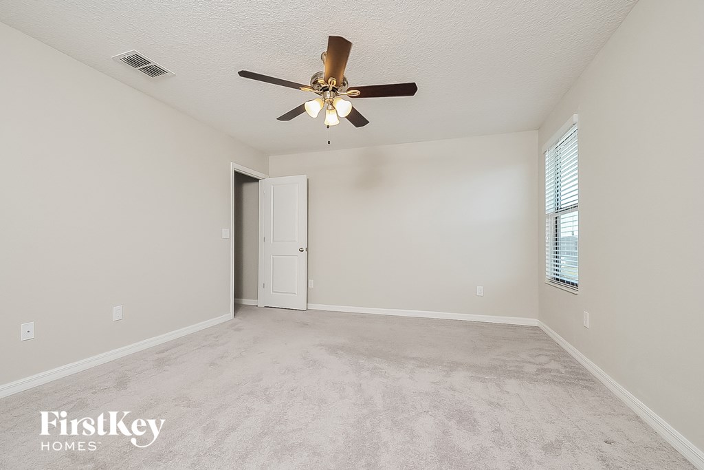 an empty living room with a ceiling fan and a door to a closet