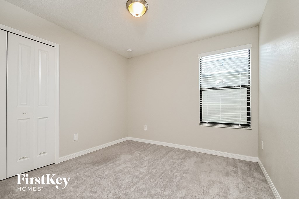 a bedroom with white carpet and a window and a white door