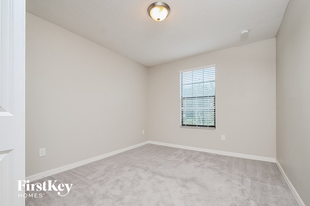 a spacious living room with white carpet and a window