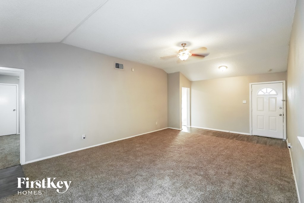A spacious room with a carpeted floor and a ceiling fan.