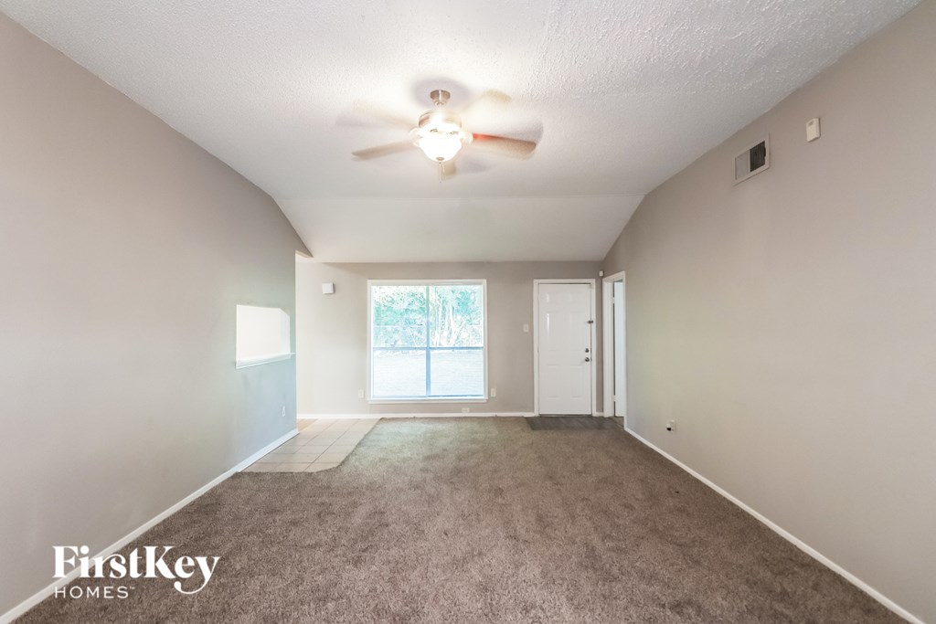 A spacious room with a ceiling fan and carpeted floor.