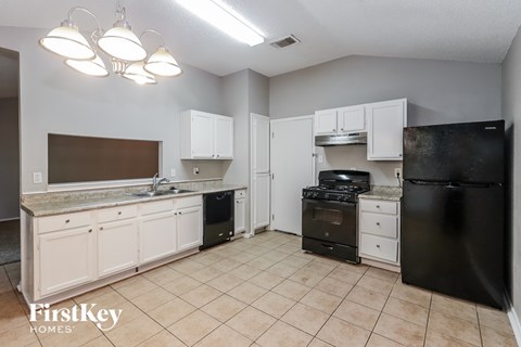 A kitchen with black appliances and white cabinets.