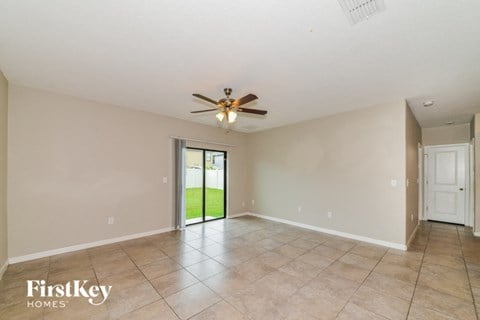 an empty living room with a ceiling fan and a door to the yard
