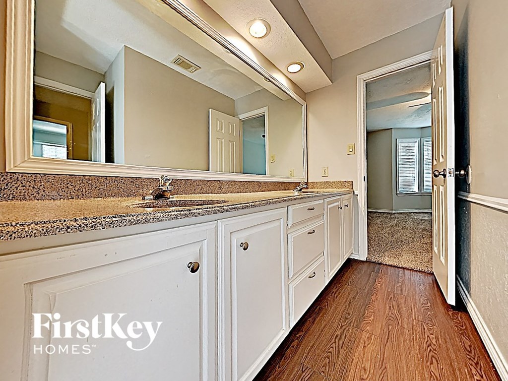 a kitchen with white cabinets and a sink and a mirror