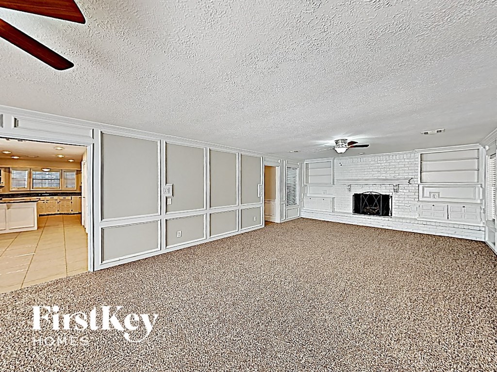an empty living room with a white brick fireplace