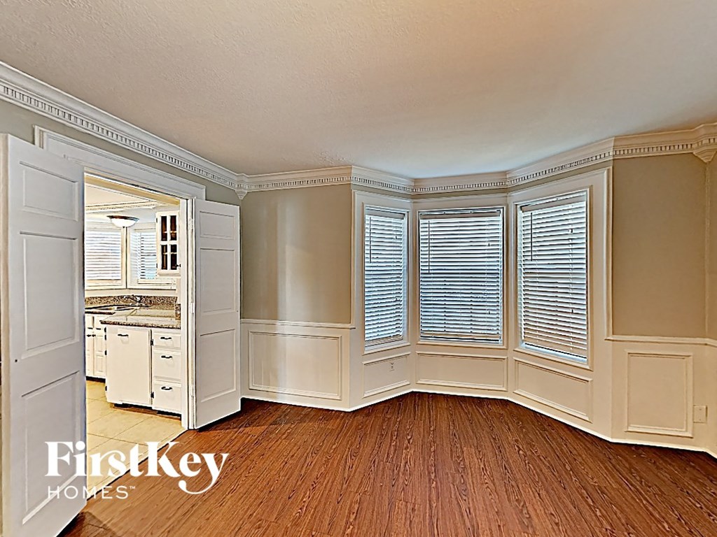 a bay window with white shutters in a kitchen with wood flooring and a