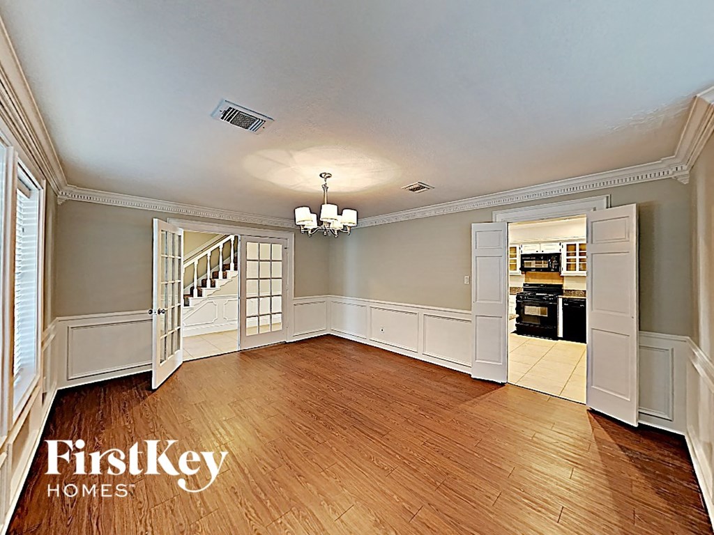 an empty dining room with wood flooring and a door way to the kitchen