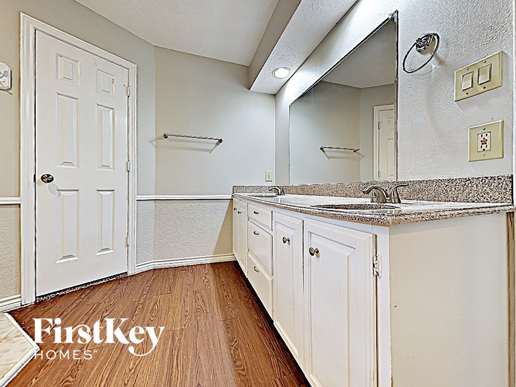 a kitchen with white cabinets and a sink and a mirror