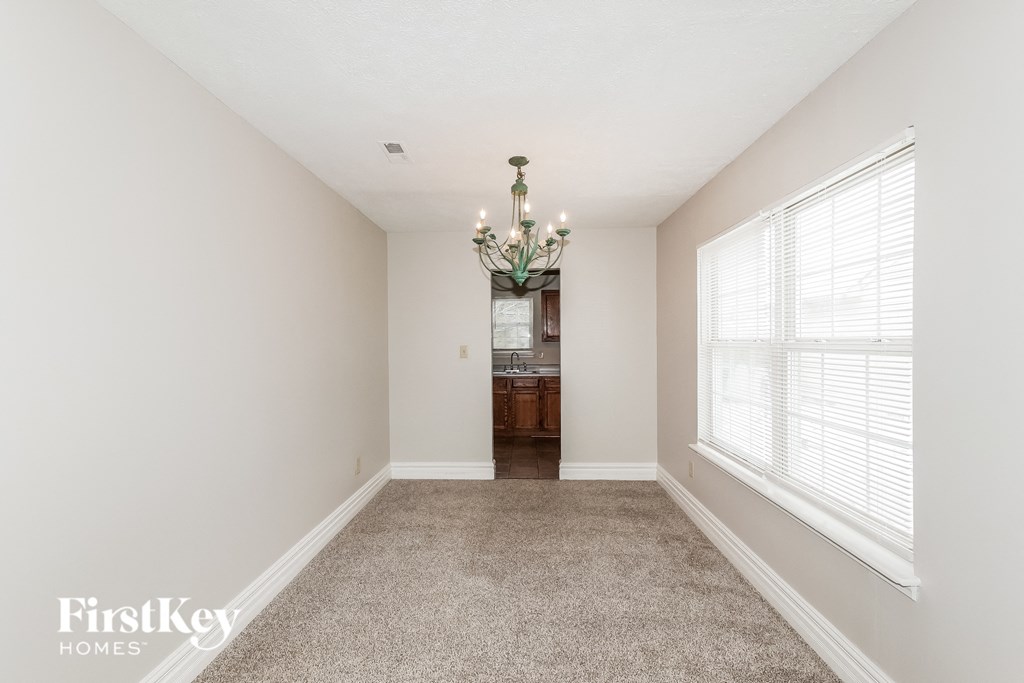 a carpeted living room with a large window and a chandelier