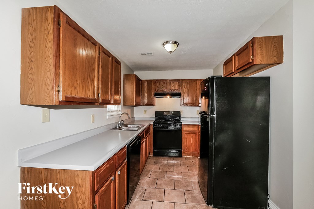 a kitchen with wood cabinets and a black refrigerator
