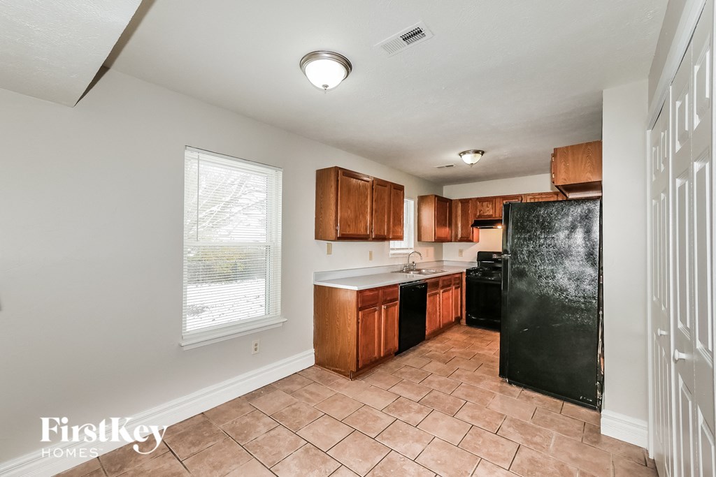 a kitchen with wooden cabinets and a black refrigerator