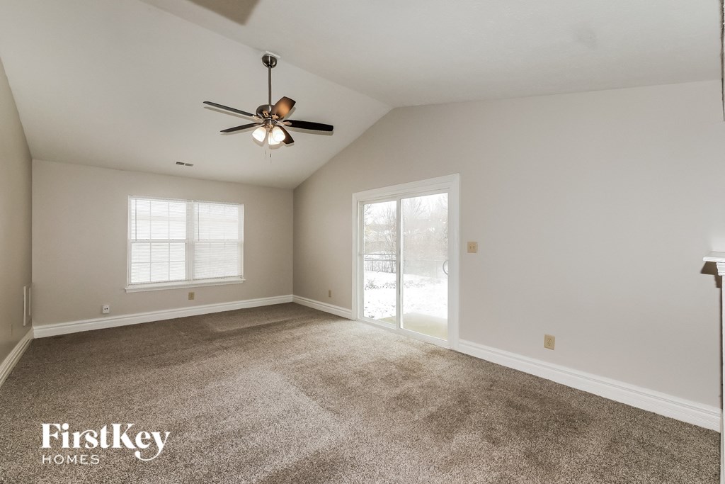 a living room with carpet and a ceiling fan