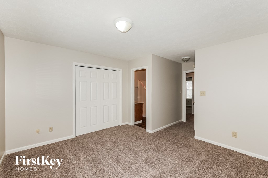 a spacious living room with carpet and a door to the bathroom