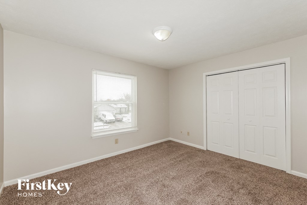 a bedroom with a carpeted floor and a door to a closet