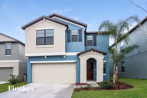 a blue and white house with a palm tree in front of it