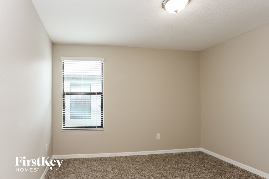 a bedroom with a window and a carpeted floor