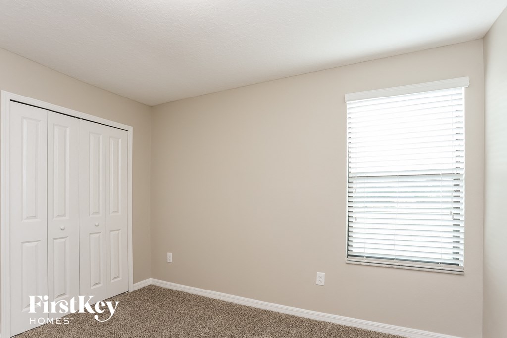 a bedroom with a closet and a window and a white door