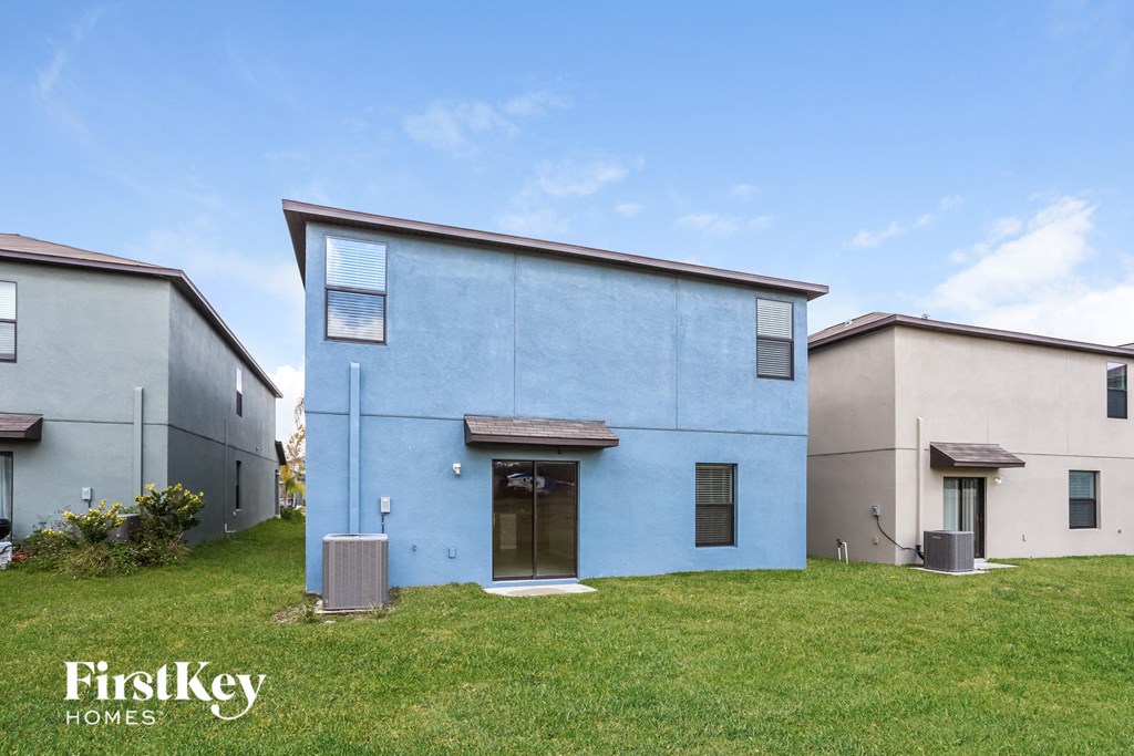 a blue house with a green lawn and two other houses