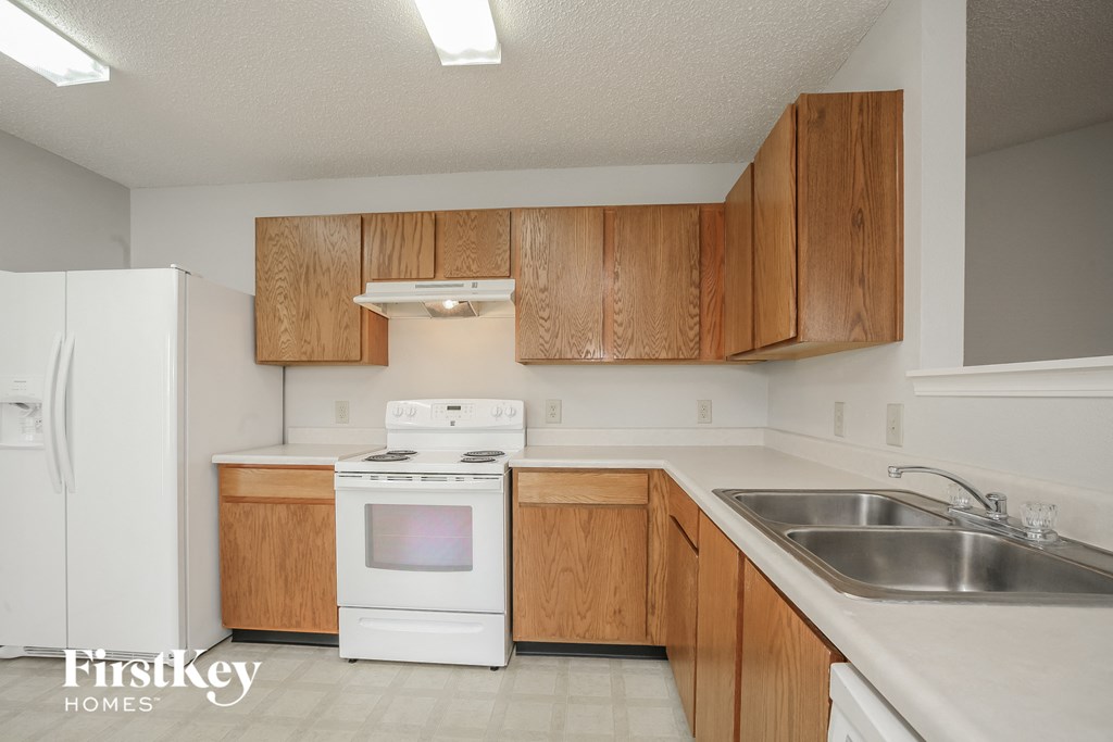 a kitchen with white appliances and wooden cabinets and a sink