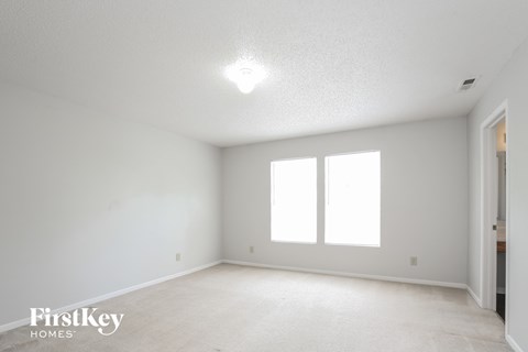 a bedroom with white walls and white carpet and two windows