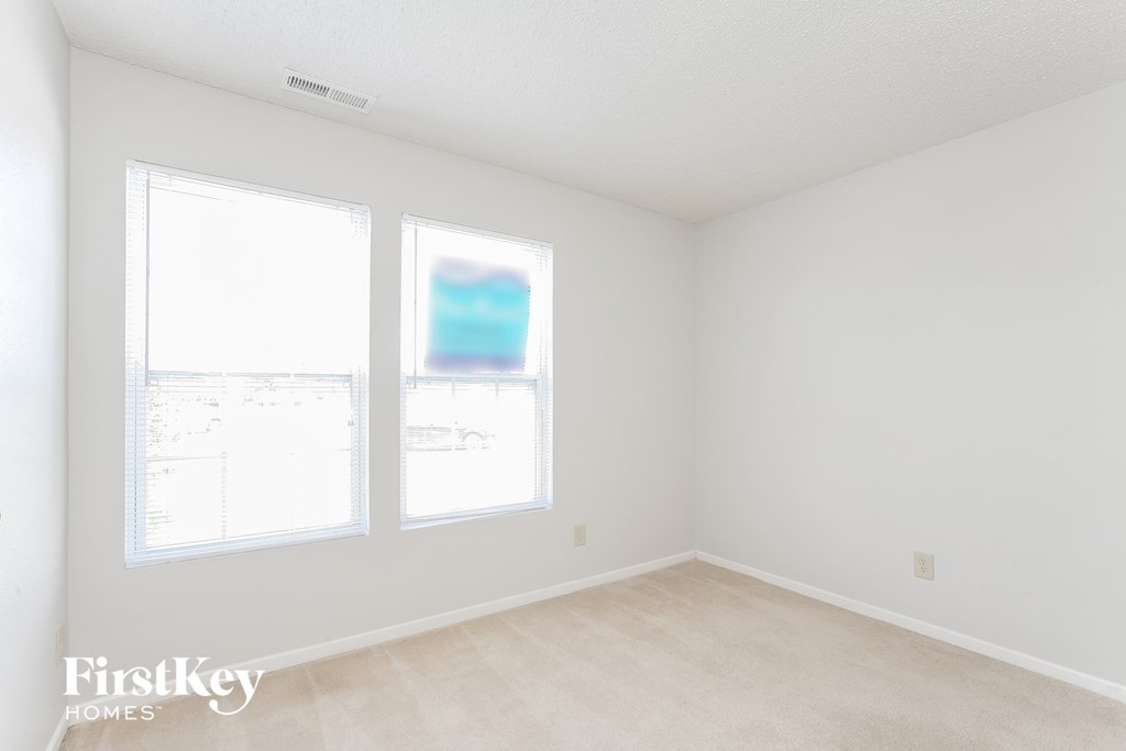 a bedroom with three windows and white walls