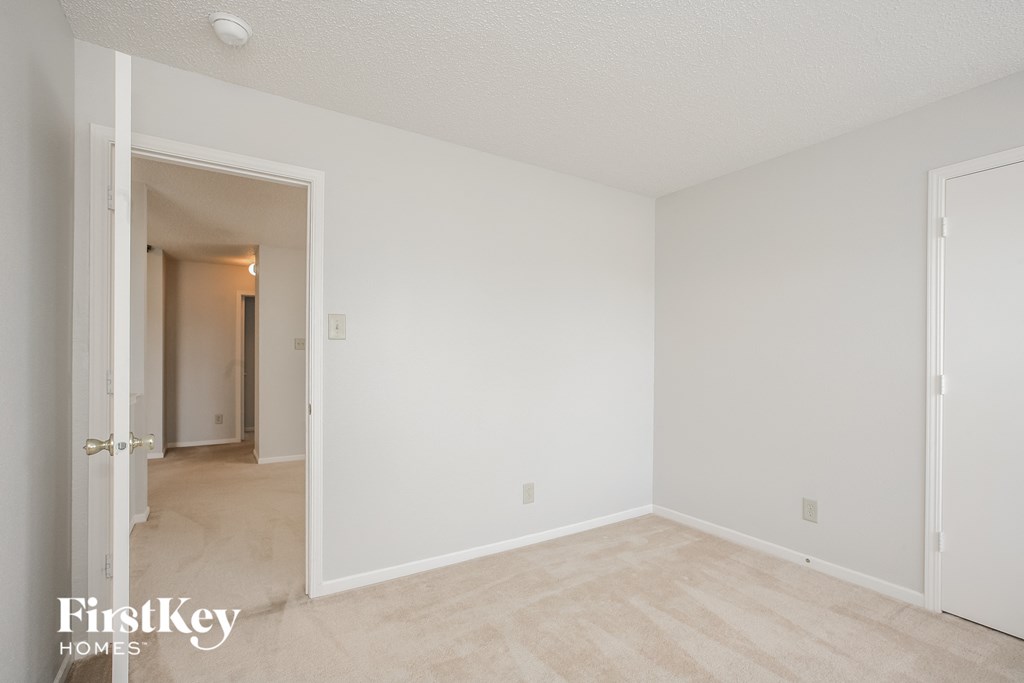 a bedroom with white walls and a door to a hallway