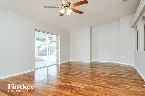 a spacious living room with hardwood flooring and a ceiling fan