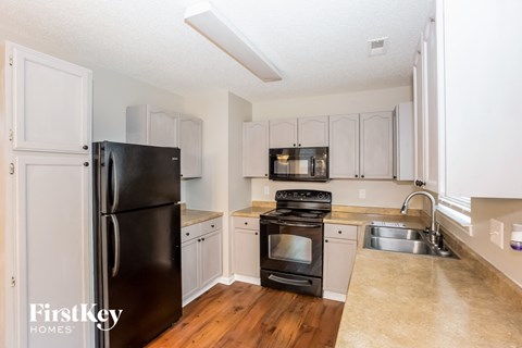 A kitchen with a black fridge and stove top oven.