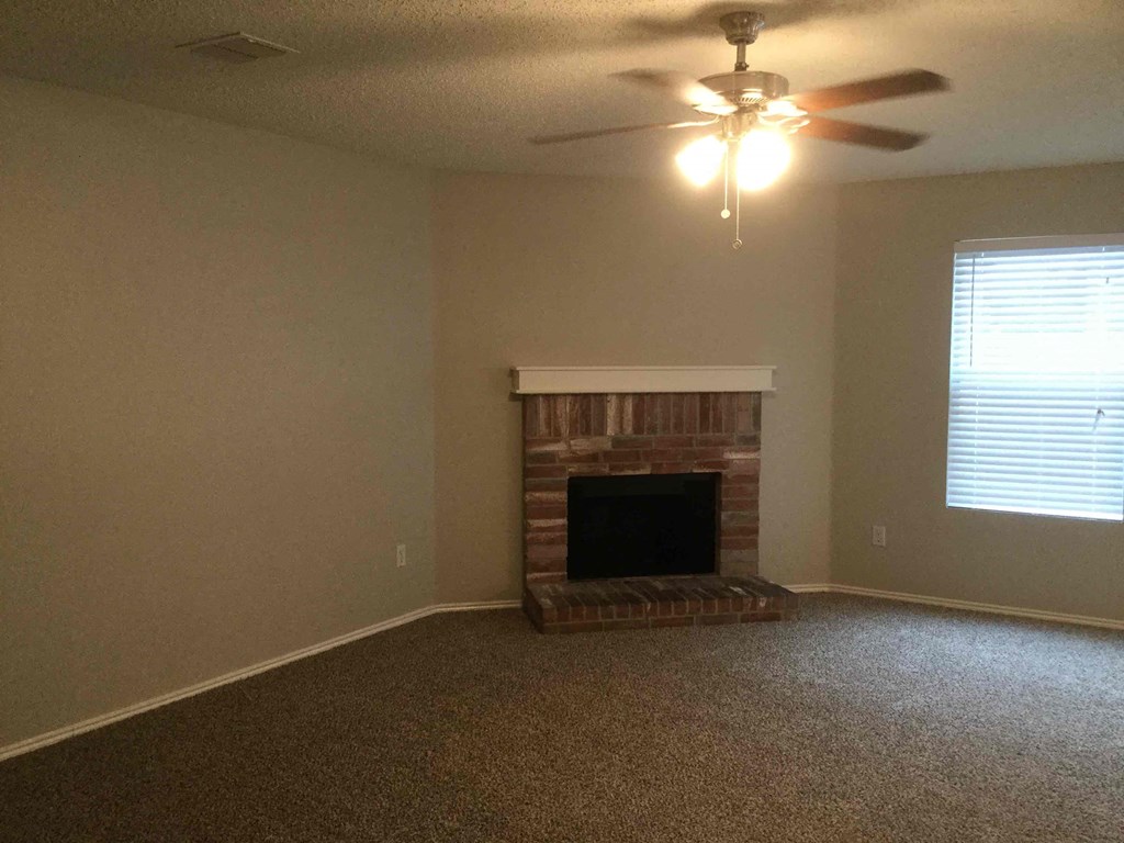 a living room with a fireplace and a ceiling fan