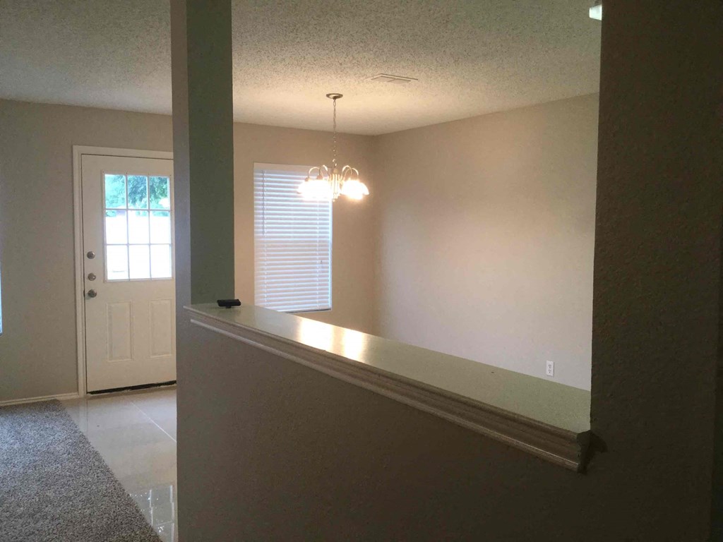 an empty living room with a long rail and a white door