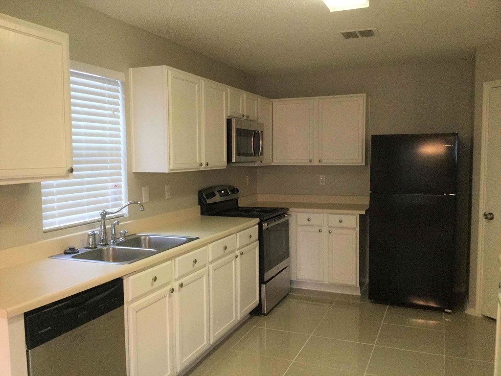 a kitchen with white cabinets and a black refrigerator