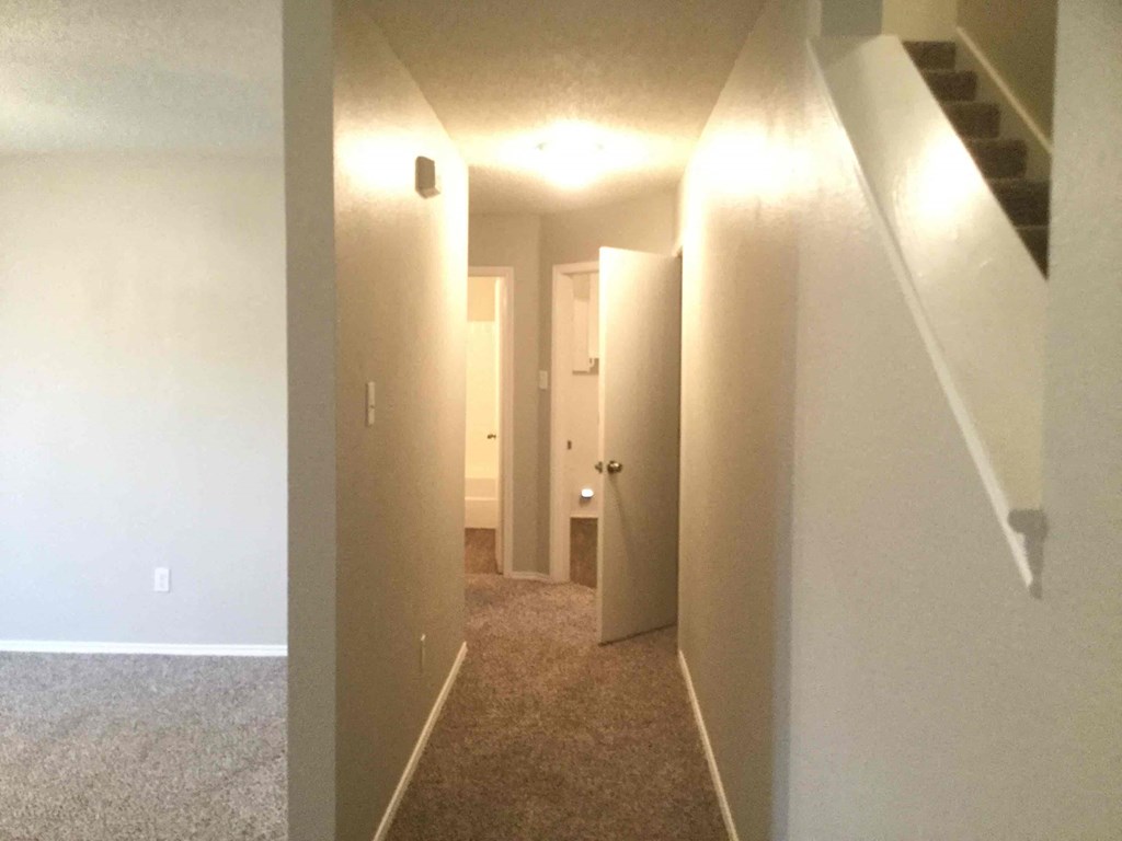 a view of a hallway with white walls and a carpeted floor