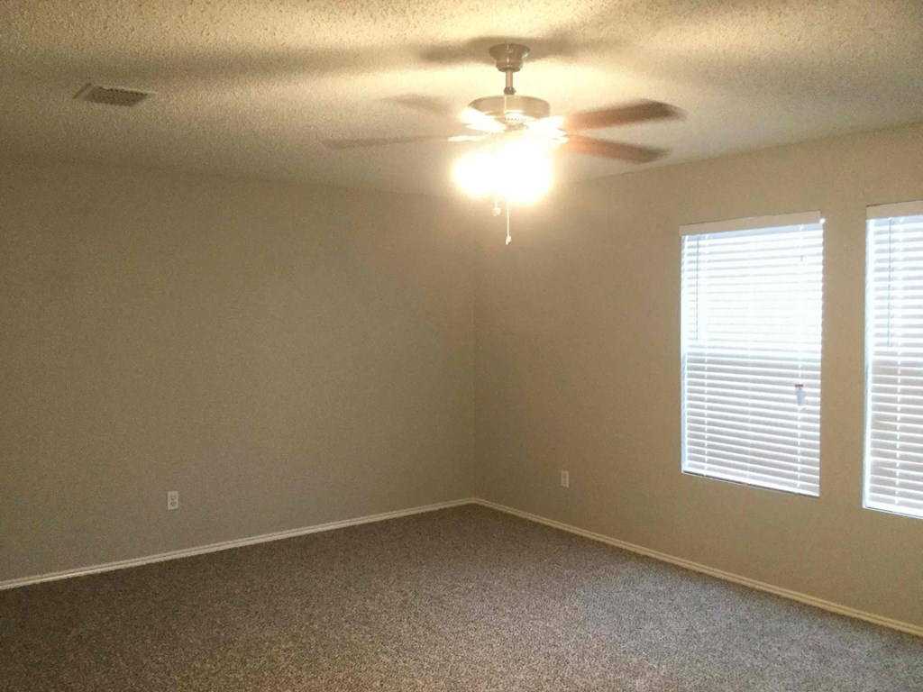 a bedroom with a ceiling fan and two windows