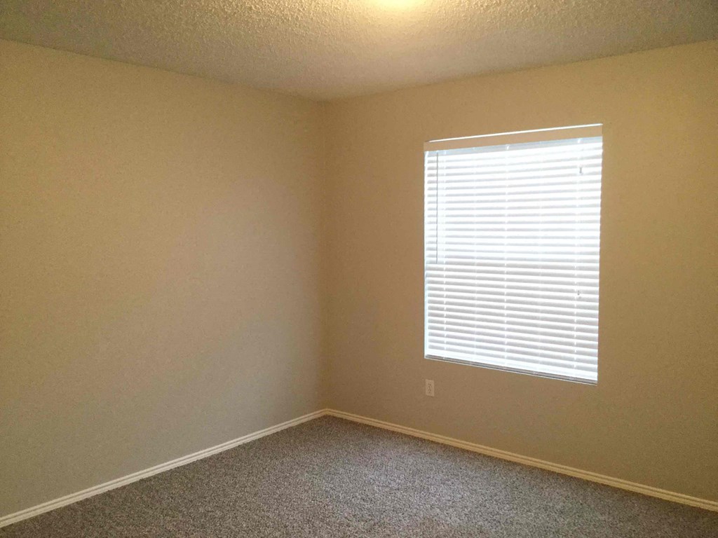 a bedroom with a window and a carpeted floor