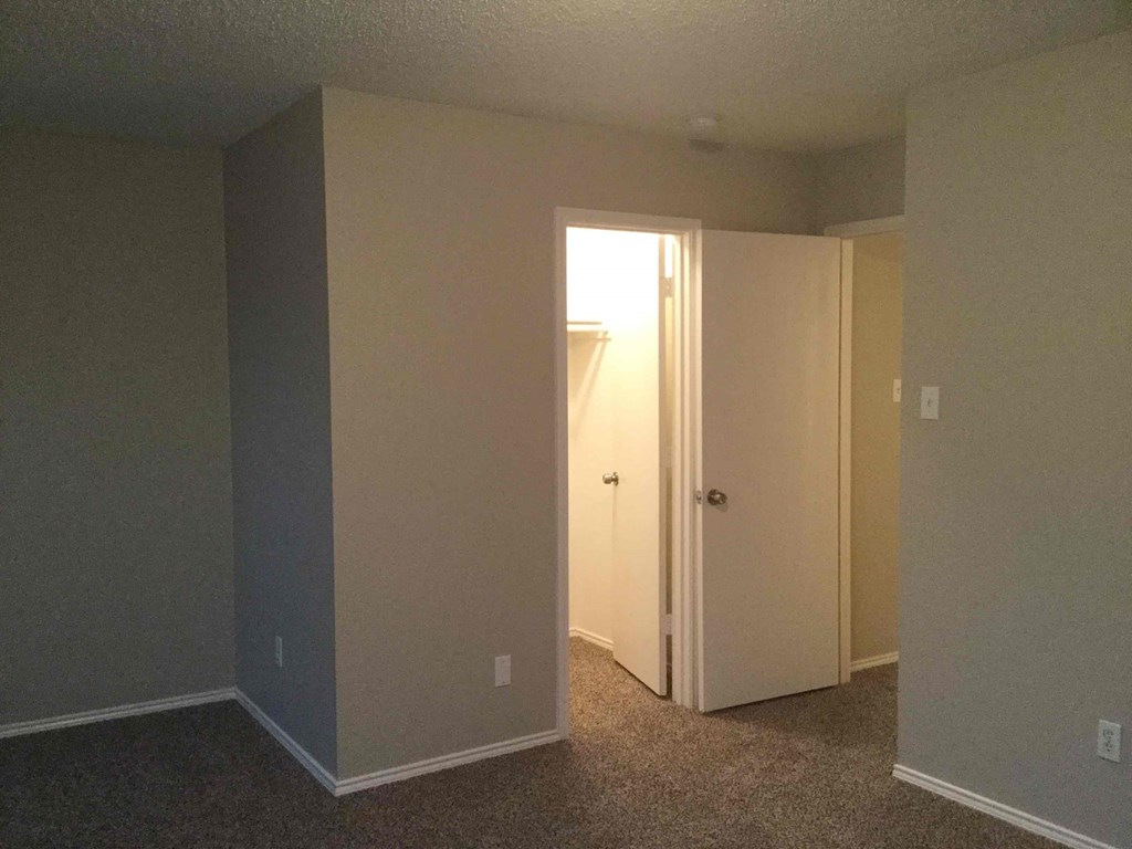 an empty room with a door open to a closet