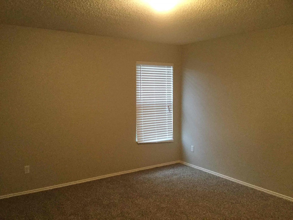 an empty room with a window and a carpet