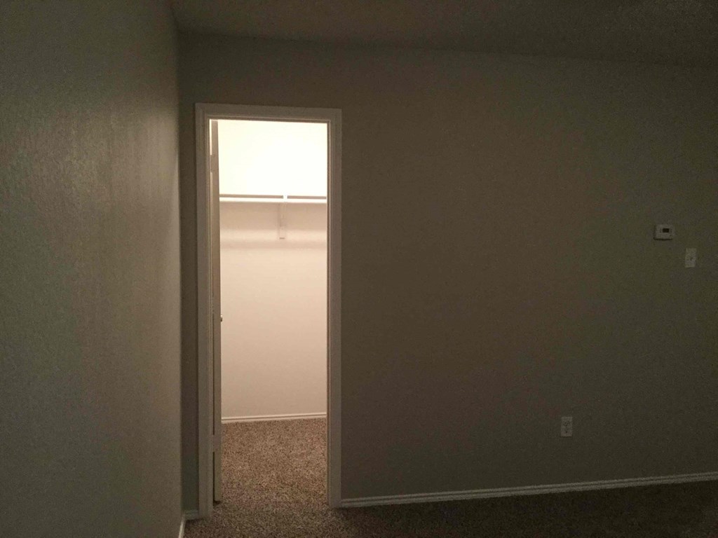 an empty room with a door open to a closet