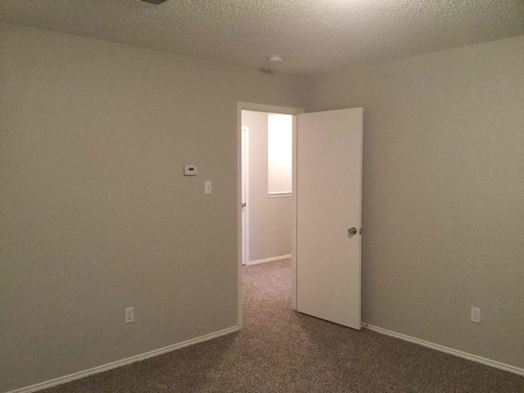an empty room with a door open to a closet