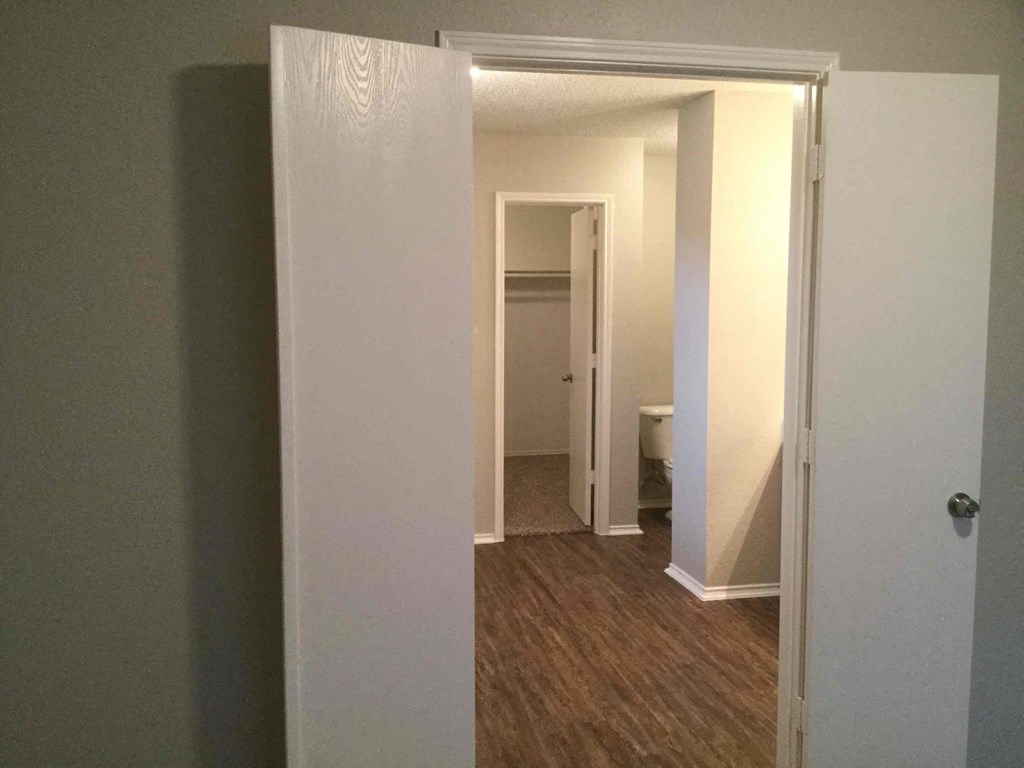 a room with a door open and a hallway with a toilet