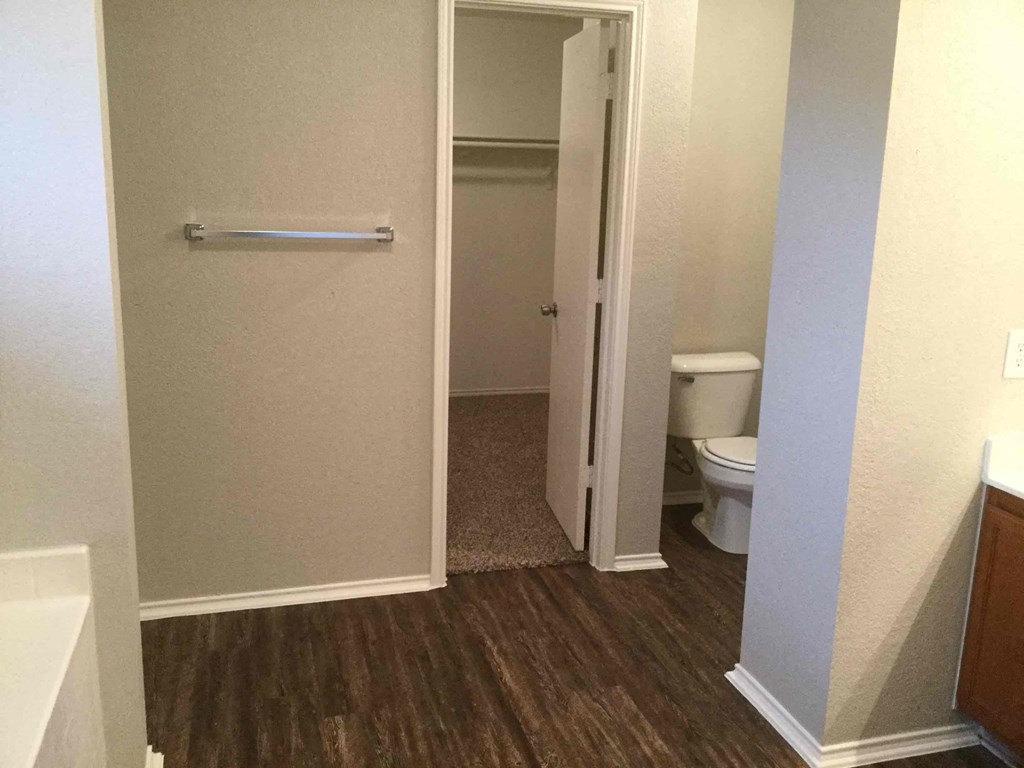 a bathroom with a toilet and a hallway with a door