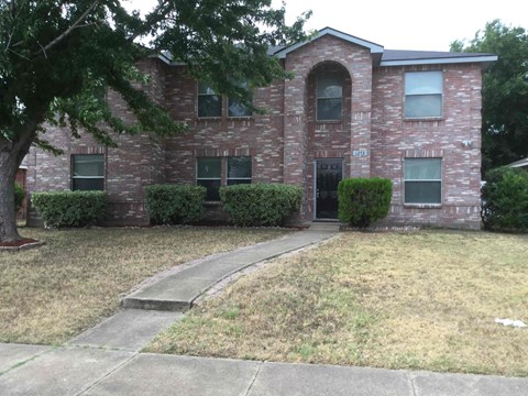 a brick house with a sidewalk in front of it