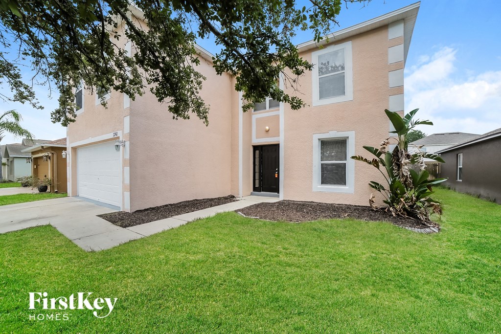 a pink house with a green lawn and a white garage door