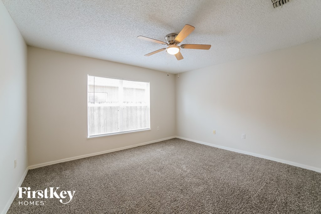 an empty room with a ceiling fan and a window
