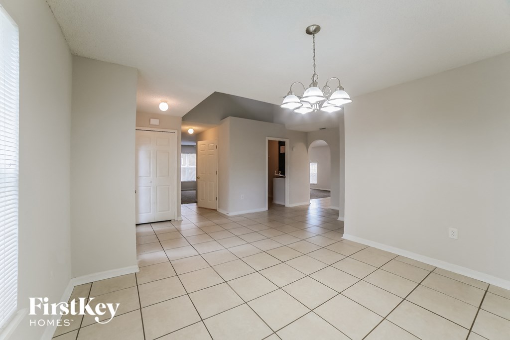 a spacious living room with tiled flooring and white walls
