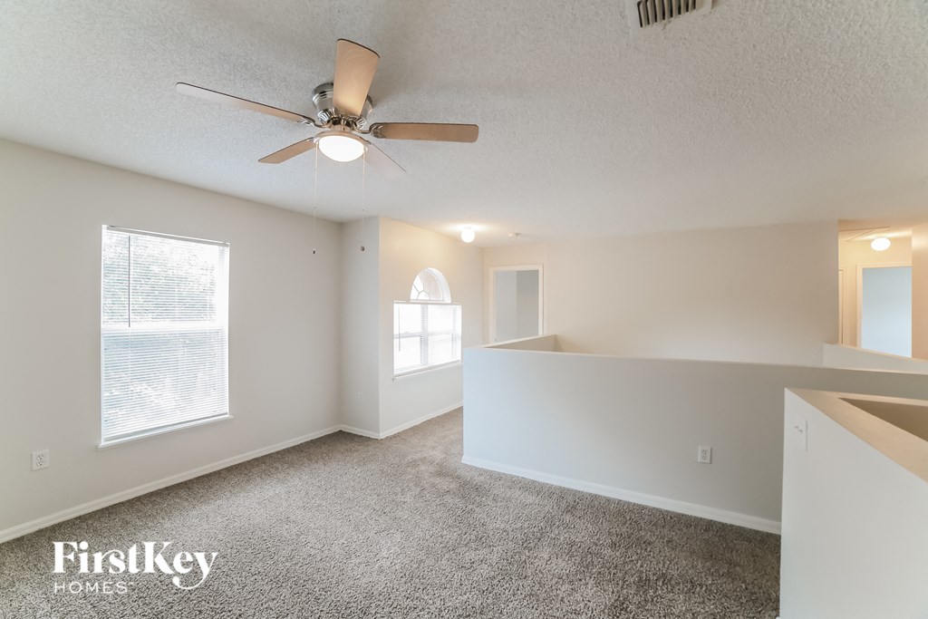 an empty living room with a ceiling fan and a window