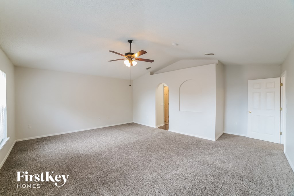 an empty living room with white walls and a ceiling fan