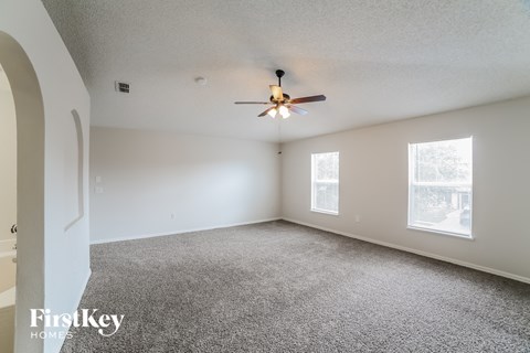 a living room with carpet and a ceiling fan