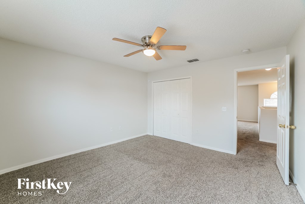 a spacious living room with a ceiling fan and a closet