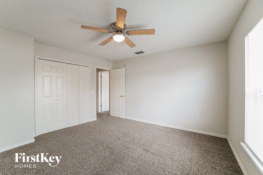 the spacious living room with ceiling fan and carpeting